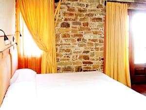 1 dormitorio con cama y pared de ladrillo en 6 bedrooms villa with private pool furnished garden and wifi at Mombarcaro en Tetti
