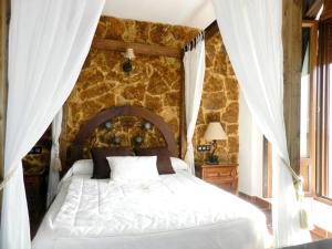 sypialnia z białym łóżkiem i kamienną ścianą w obiekcie Elegant villa in Padul with private pool w mieście Padul