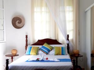 a bedroom with a bed with colorful pillows at Studio accueillant à Baie Mahault - 20 m² avec piscine privée in Baie-Mahault