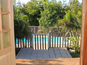 una puerta que conduce a una piscina con una valla y árboles en Chalet d'une chambre avec piscine partagee jardin et wifi a Bouillante a 1 km de la plage, en Bouillante