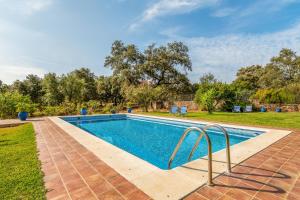 a swimming pool in a yard with chairs and trees at 4 bedrooms villa with private pool and enclosed garden at Cortegana in Cortegana