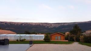 una casa con un invernadero y montañas al fondo en Appartement moderne avec piscine à Plan-d'Aups 55 m² - Spa inclus​, en Plan dʼAups