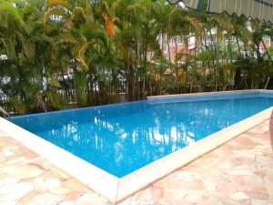 a blue swimming pool with trees in the background at Charmant Bungalow avec Piscine Partagée à Le Gosier in Le Gosier