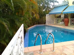 een zwembad naast een villa met een huis bij Bungalow d'une chambre avec piscine partagee jardin clos et wifi a Le Gosier in Le Gosier