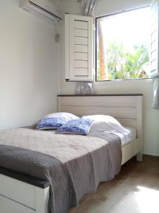 a bed with two pillows in a bedroom with a window at Charmant Bungalow avec Piscine Partagée à Le Gosier in Le Gosier +15 photos