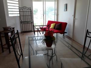 a living room with a red couch and a glass table at Appartement d'une chambre avec terrasse et wifi a Les Abymes a 9 km de la plage in Les Abymes