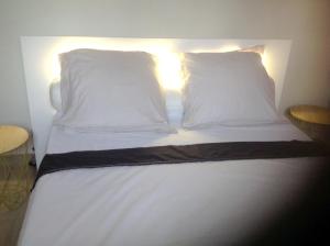 una cama con almohadas blancas y una luz en ella en Appartement de 2 chambres avec balcon et wifi a Les Abymes a 7 km de la plage, en Les Abymes