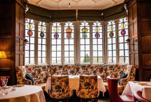 a restaurant with a couch and tables and stained glass windows at Ellenborough Park in Cheltenham