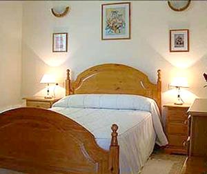 1 dormitorio con 1 cama de madera, 2 mesitas de noche y 2 lámparas en 2 bedrooms villa with private pool garden and wifi at La Calzada de Bejar, en La Calzada de Béjar