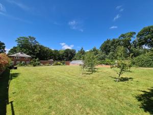 a large grassy field with trees and a house at Sloley Hall Cottages - Stable 1 in Tunstead