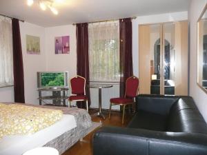 a bedroom with a bed and a couch and a tv at City Hotel in Ludwigsburg