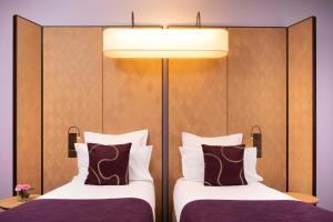 two beds in a hotel room with a headboard at Hotel Maison FL in Paris