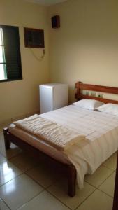 Schlafzimmer mit einem großen Bett und einem Kühlschrank in der Unterkunft Diplomata Hotel in Araras