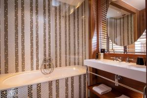 a bathroom with a tub and a sink and a mirror at Hotel Maison FL in Paris