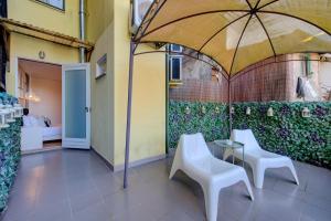 un patio con 2 sillas blancas y una sombrilla en Bellu Suites en Guimarães