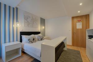 - une chambre avec un lit blanc et des rayures bleues dans l'établissement Bellu Suites, à Guimarães