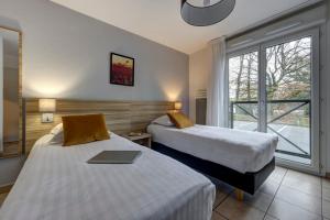 a hotel room with two beds and a window at Comfort Aparthotel Divonne L'Orée du Parc in Divonne-les-Bains