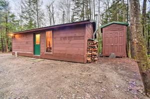 una cabaña de madera en el bosque junto a un árbol en Charming Rural Retreat Great Sacandaga Lake Area!, en Benson
