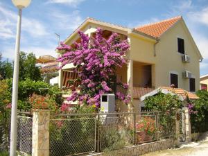 una casa con flores púrpuras delante de una valla en Apartments Biskup, en Privlaka