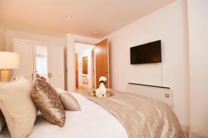 a bedroom with a bed with a television on the wall at Deluxe City Centre Apt Balcony View& Free Parking! in Leeds