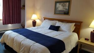 Cama grande en habitación de hotel con manta azul en Eastern Inn & Suites (formerly Eastern Inns), en North Conway