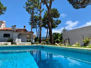 a swimming pool in front of a house with trees at Oak Valley Flats Casa do Pinhal Colares in Colares