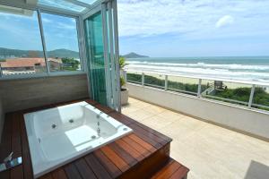 a bath tub on a balcony with a view of the ocean at Hospedaria Home Suites Mariscal in Bombinhas