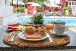einen Frühstückstisch mit Frühstückszutaten und Getränken auf einem Tisch am Pool in der Unterkunft Pousada Tartaruga in Búzios