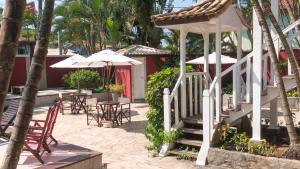 un patio con mesas, sillas y sombrillas en Pousada Tartaruga, en Búzios