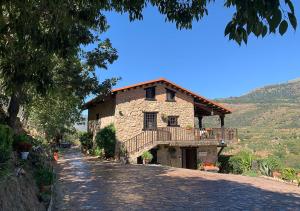 a large stone house with a balcony on a road at La Seguirilla del Jerte in Casas del Castañar