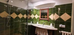 a green tiled bathroom with a sink and a mirror at Ca la Caterina in Peratallada