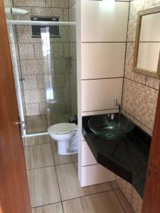 a bathroom with a toilet and a glass sink at Residencial Sandini Garopaba in Garopaba