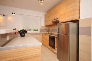 a kitchen with wooden cabinets and a stainless steel refrigerator at Apartman MAKA in Kučiće