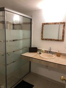 a bathroom with a sink and a glass shower at Casa en Oasis en Xochitepec in Chiconcuac