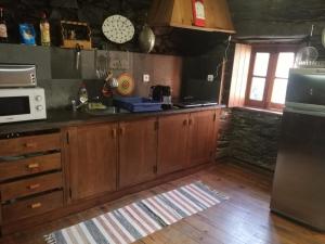 cocina con armarios de madera y microondas en Casa das Tias, en Lousã