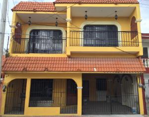 une maison jaune avec un toit rouge dans l'établissement Apartamento Colonial Campeche, à Campeche
