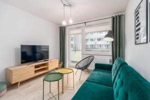 ein Wohnzimmer mit einem grünen Sofa und Stühlen in der Unterkunft FARO Apartamenty Bliżej Morza in Kołobrzeg