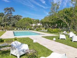 einen Pool mit weißen Stühlen und einen Hof in der Unterkunft Hôtel L'Hermitage in Pernes-les-Fontaines