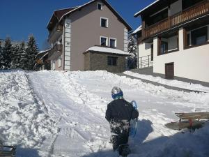 una persona caminando en la nieve con una tabla de snowboard en GOLD apartamenty & spa, en Szczawnica