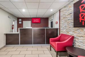 a waiting room with a red chair and a table at Red Roof Inn & Suites Wapakoneta in Wapakoneta