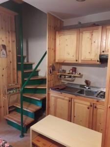 a kitchen with wooden cabinets and a green staircase at Abetone - Parco dei Daini in Abetone