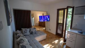 a living room with a couch and a flat screen tv at Уютная квартира в тени старого дуба in Becici +7 photos