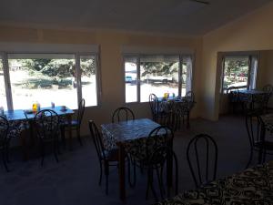 un comedor con mesas, sillas y ventanas en Hotel Silver Golf en Sierra de la Ventana