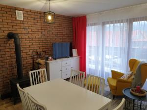 - un salon avec une télévision, une table et des chaises dans l'établissement Apartament Gaia, à Kościelisko