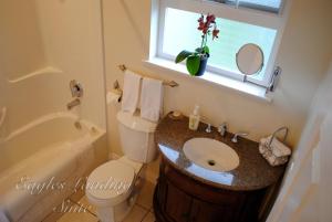 a bathroom with a sink and a toilet and a window at Corbett Guest Suites in Sidney