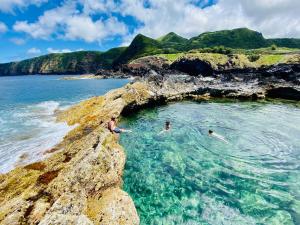 three people swimming in the ocean on a rocky shore at Sea Roots "Sea Zone" in Mosteiros