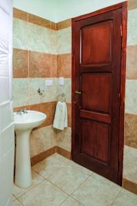 a bathroom with a sink and a wooden door at Cabañas Villa del Sol in Salta