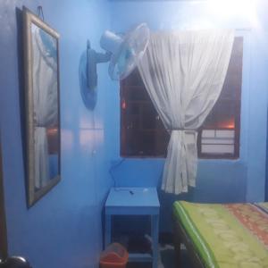 a bedroom with blue walls and a window and a table at CVBNB BAGUIO GUESTHOUSE in Baguio