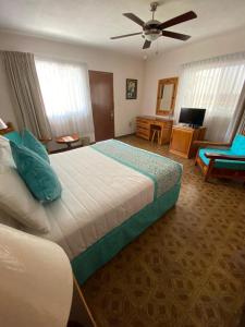 a bedroom with a large bed with a ceiling fan at Hotel Posada Quinta Las Flores in Cuernavaca