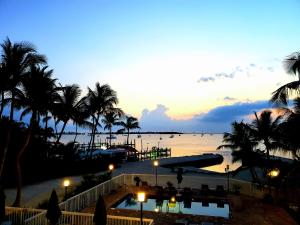 um pôr-do-sol sobre uma praia com palmeiras e uma piscina em Bayside Inn Key Largo em Key Largo
